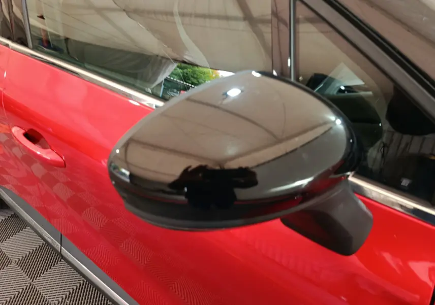 Rétroviseur noir en gros plan côté gauche sur une Renault Captur Techno TCe 90 rouge 2024.