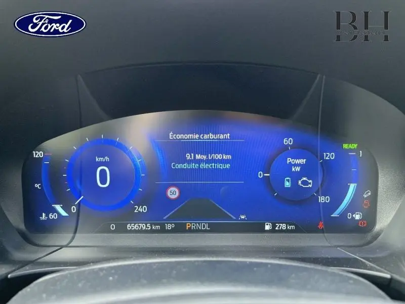 Tableau de bord numérique du Ford Kuga hybride 2022 affichant la consommation et la vitesse à 0 km/h.