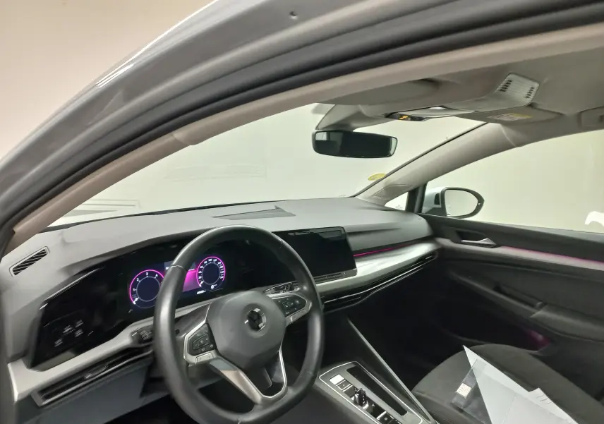 Vue intérieure côté conducteur de la Volkswagen Golf 2.0 TDI 116 DSG7 Life Plus 2023 en reflet d'argent avec éclairage d'ambiance violet.