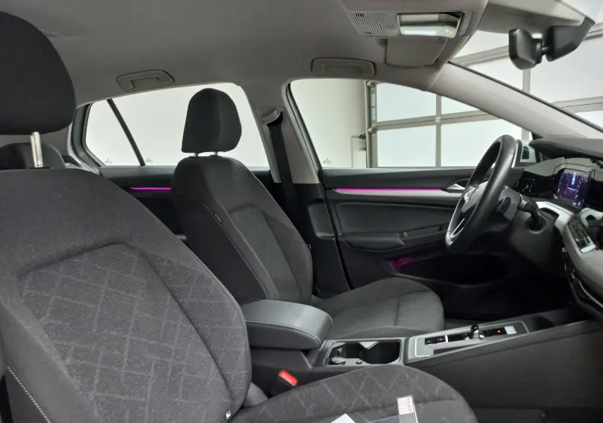 Intérieur avant droit de Volkswagen Golf 2.0 TDI 116 DSG7 Life Plus 2023, sièges tissu noirs et éclairage d'ambiance violet.