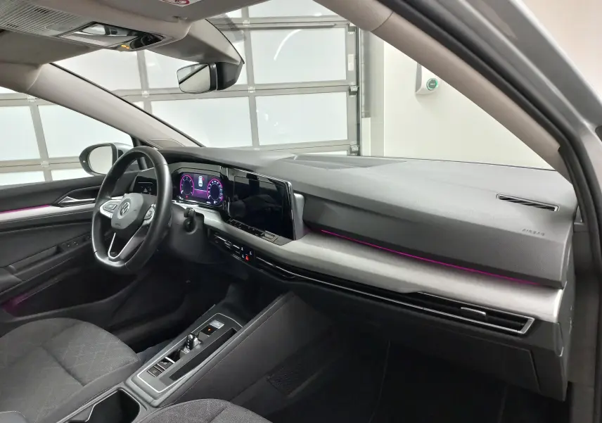 Vue intérieure côté conducteur de la Volkswagen Golf 2.0 TDI 116 DSG7 Life Plus 2023 avec éclairage d'ambiance violet et tableau de bord moderne.