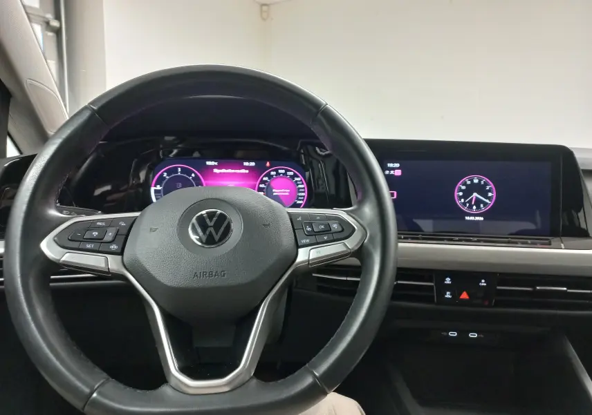 Vue intérieure centrée sur le volant noir et le tableau de bord numérique d'une Volkswagen Golf 2023 reflet d'argent.