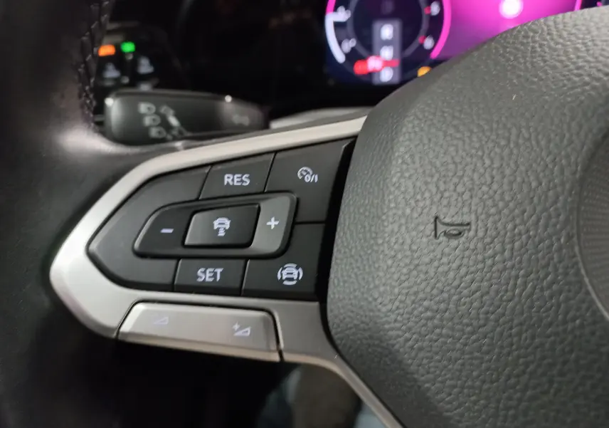 Gros plan sur les commandes de régulateur de vitesse au volant d’une Volkswagen Golf 2.0 TDI 2023 couleur reflet d'argent.