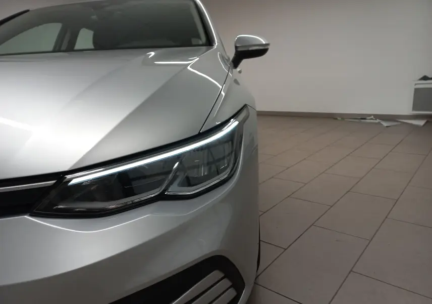 Vue rapprochée avant droite d’une Volkswagen Golf 2.0 TDI 116 DSG7 Life Plus 2023 en reflet d’argent avec phares LED allumés.