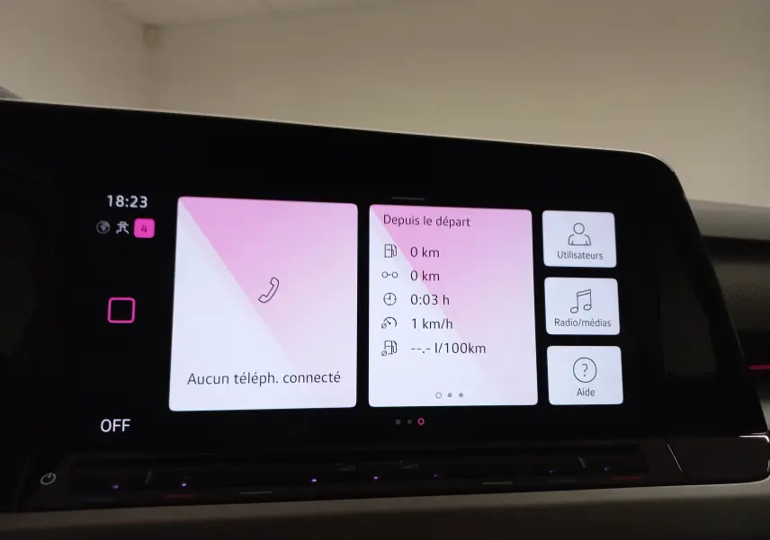 Écran tactile central de la Volkswagen Golf 2023 affichant l'interface multimédia avec fond rose pâle.