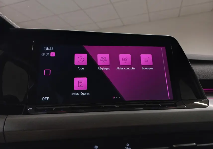 Écran tactile central affichant le menu des réglages avec interface en violet à l'intérieur d'une Volkswagen Golf 2023 reflet d'argent.