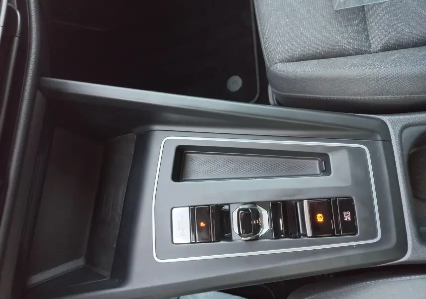 Vue plongeante sur la console centrale noire de la Volkswagen Golf 2.0 TDI 116 DSG7 Life Plus avec levier de vitesse électronique et boutons éclairés.