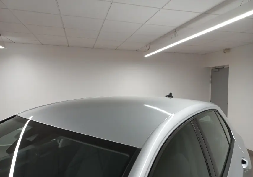 Vue rapprochée du toit et du côté gauche d'une Volkswagen Golf 2.0 TDI argentée dans un intérieur neutre.
