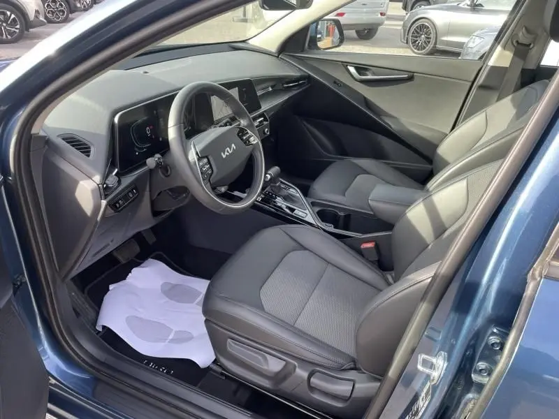Intérieur côté conducteur du KIA Niro 2024 bleu métal, montrant le tableau de bord moderne et les sièges en tissu gris.