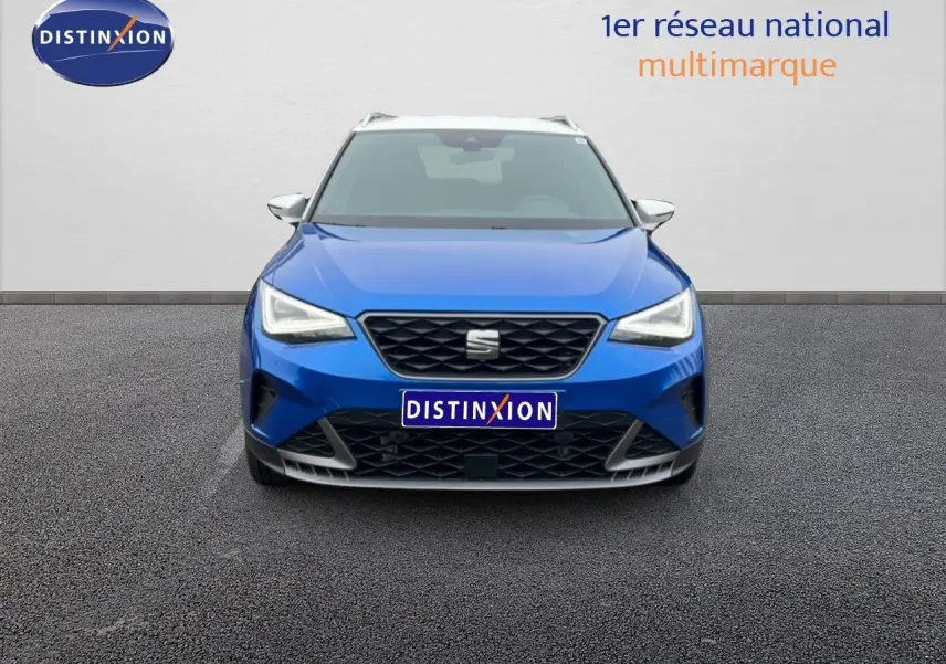 Vue avant d'un SEAT Arona bleu saphir métal avec toit blanc, calandre noire et phares LED allumés.