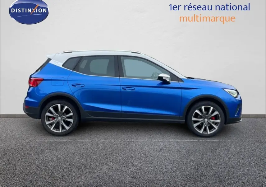 Vue de profil côté gauche d'un SEAT Arona 2025 bleu saphir métallisé avec toit blanc et jantes alliage noires.