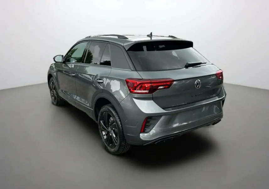 Vue 3/4 arrière du Volkswagen T-Roc gris indium avec jantes noires et vitres surteintées dans un studio.