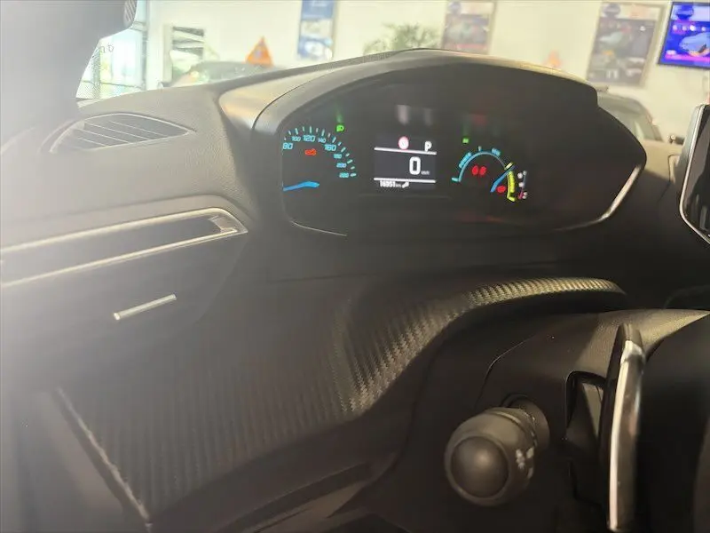 Vue rapprochée du tableau de bord noir du Peugeot 2008 Hybrid 145ch, avec affichage digital et détails lumineux colorés.