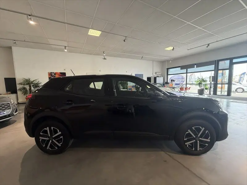 Peugeot 2008 Hybrid 145ch noir métal, vue de profil côté gauche en intérieur de showroom lumineux.