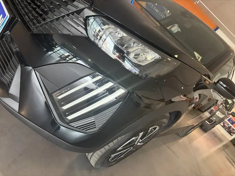 Vue 3/4 avant droit du Peugeot 2008 hybride noir métal, mettant en valeur ses phares LED et jantes modernes.