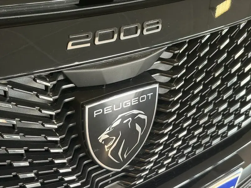 Gros plan sur la calandre noire métal du Peugeot 2008 avec logo lion et inscription du modèle en relief.