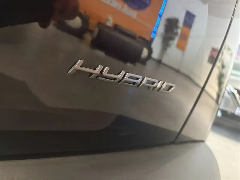 Gros plan sur l’inscription "HYBRID" en chrome sur la carrosserie noire métal d’un Peugeot 2008.
