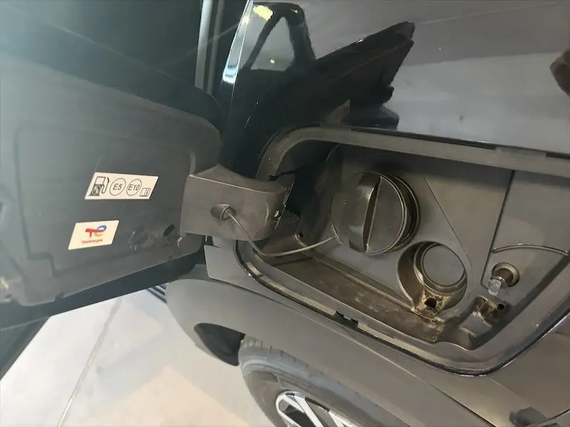 Gros plan sur la trappe à carburant noire métal du Peugeot 2008 Hybrid 145ch, côté gauche arrière, avec bouchon ouvert.