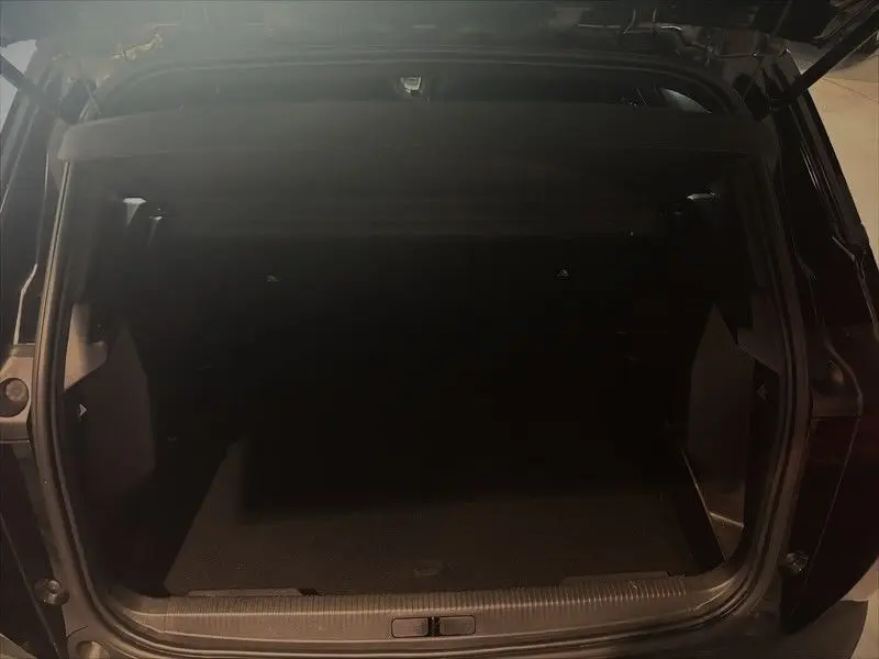 Coffre ouvert vu de l'arrière d'un Peugeot 2008 noir métal, montrant l'espace de chargement vide.