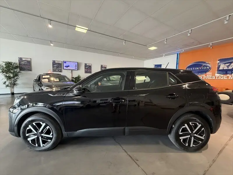Vue de profil côté gauche d’un Peugeot 2008 Hybrid noir métal exposé en showroom avec jantes noires et argent.