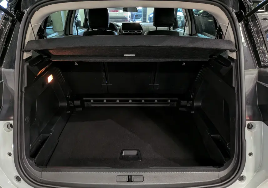 Vue arrière du coffre ouvert du Citroën C5 Aircross blanc Okénite avec toit noir, montrant l’espace de chargement vide et l’éclairage intérieur.