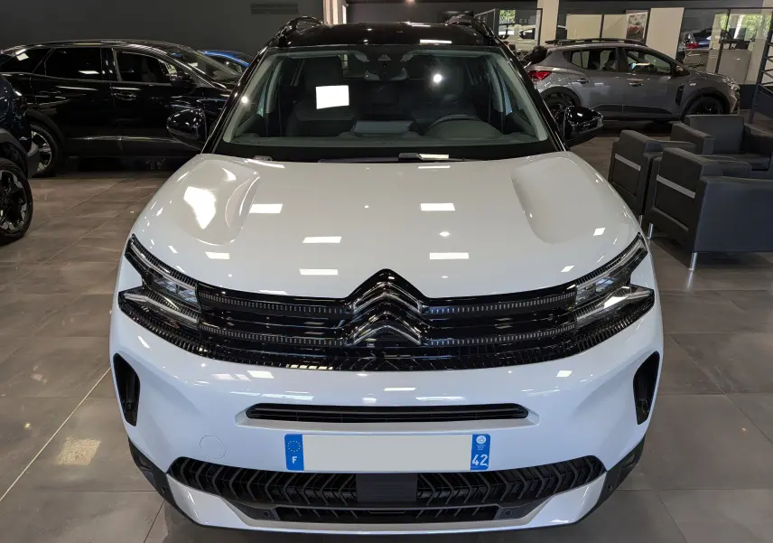 Vue avant d'un Citroën C5 Aircross 2025 blanc Okénite avec toit noir, calandre noire brillante et éclairage LED fin.