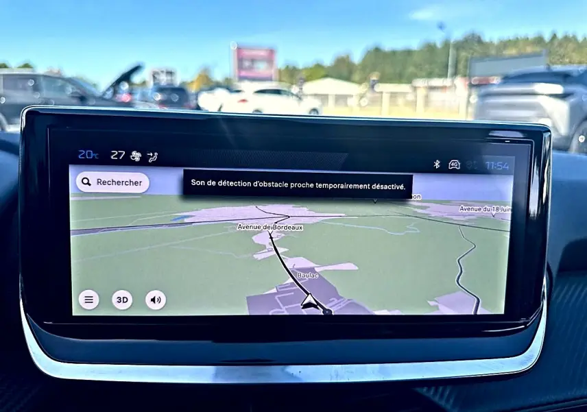 Écran tactile central du tableau de bord de la Peugeot 208 noire, affichant la navigation GPS en plein jour.