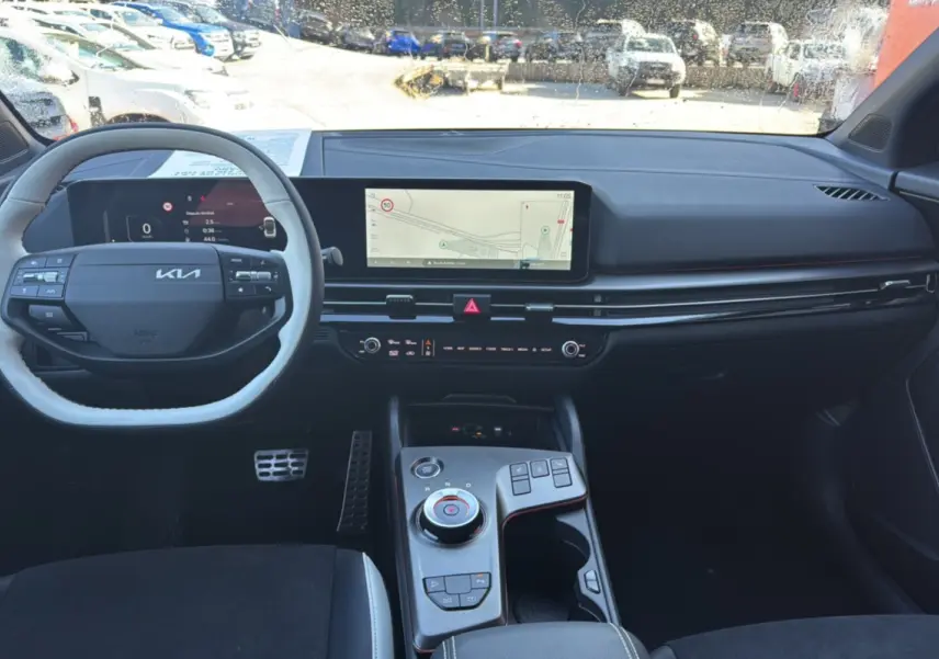 Vue intérieure avant du Kia Sportage 2026, tableau de bord noir avec écran central large et volant multifonctions.