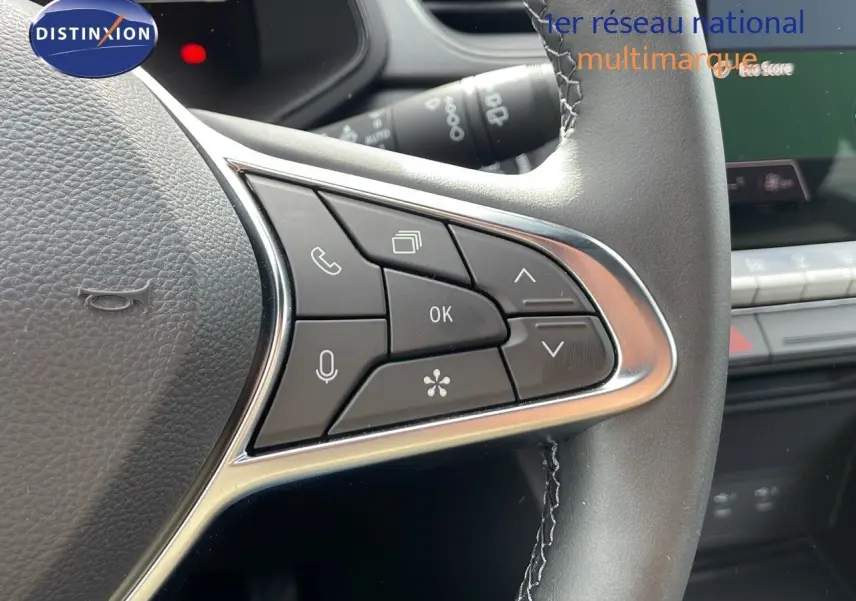 Gros plan sur les commandes du volant du Renault Captur gris cassiopée métal avec toit noir, version hybride 2025.