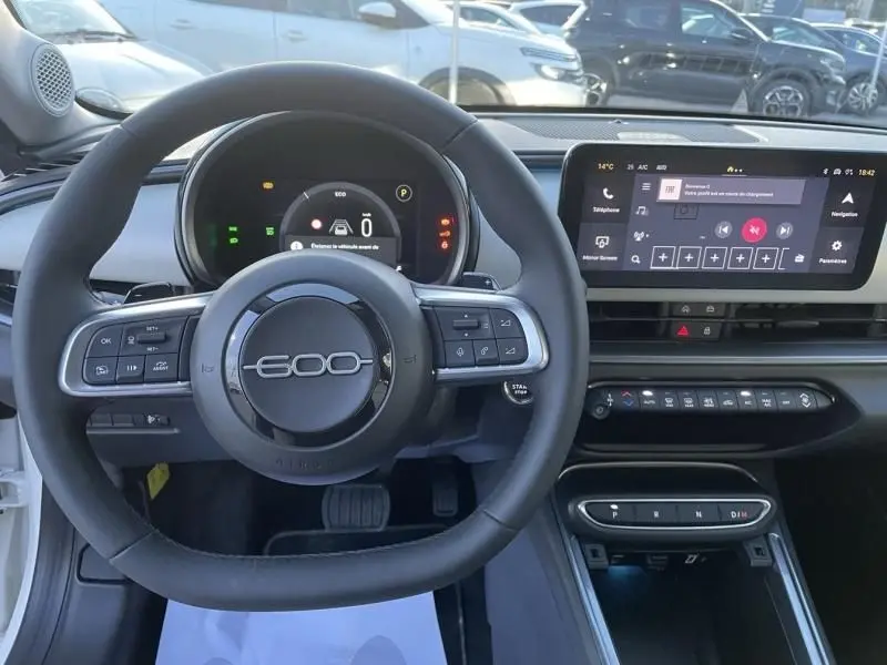 Vue intérieure centrée sur le volant noir avec logo 600 et tableau de bord numérique de la Fiat 600 blanche 2025.