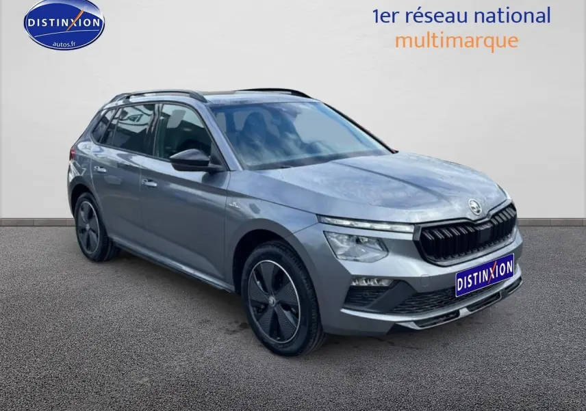 Vue 3/4 avant droite d'un Skoda Kamiq gris graphite avec jantes alu et barres de toit noires.