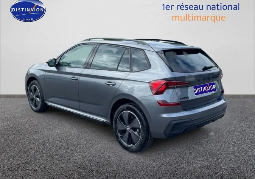 Vue 3/4 arrière droite d'un Skoda Kamiq gris graphite avec jantes alu noires et barres de toit.