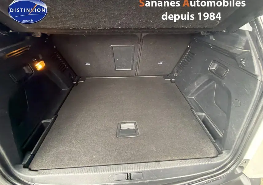 Coffre ouvert du Peugeot 3008 blanc nacré, vue intérieure montrant le plancher plat et les parois noires.