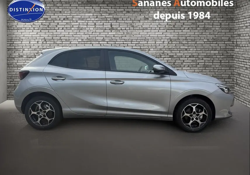 Vue latérale droite du MG3 1.5 Hybrid+ 195 Luxury en Cosmic Silver avec jantes distinctives, sur fond de mur en briques.