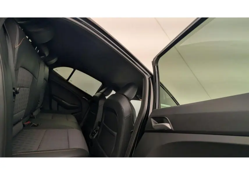 Vue intérieure arrière côté gauche de la MG3 1.5 Hybrid+ 2026 avec sellerie tissu/similicuir noir et porte ouverte.