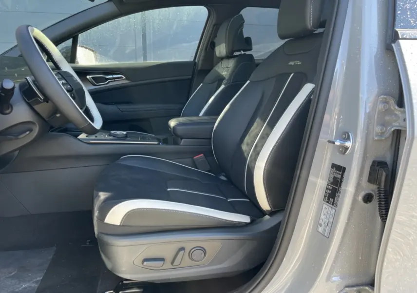 Vue intérieure côté conducteur du Kia Sportage gris céramique, sièges sport noirs avec surpiqûres blanches et logo GT.