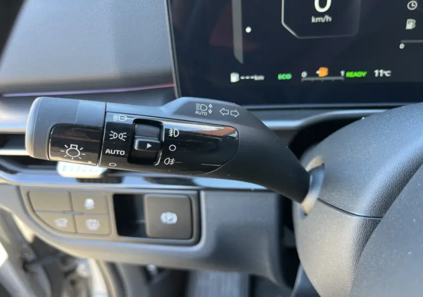 Gros plan sur la commande des feux et clignotants à gauche du volant du Kia Sportage gris céramique 2026.