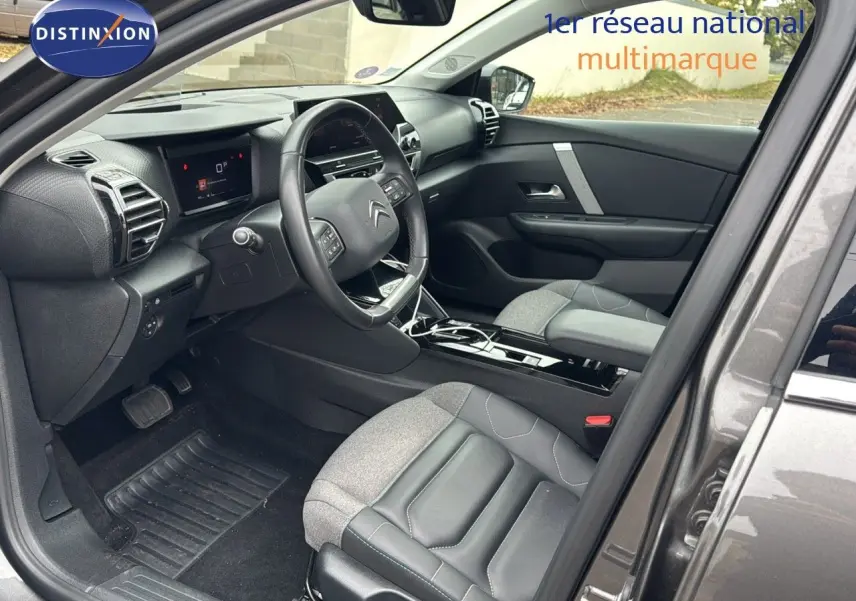 Intérieur côté conducteur d'une Citroën C4 gris toit noir, avec tableau de bord moderne et sièges cuir gris.