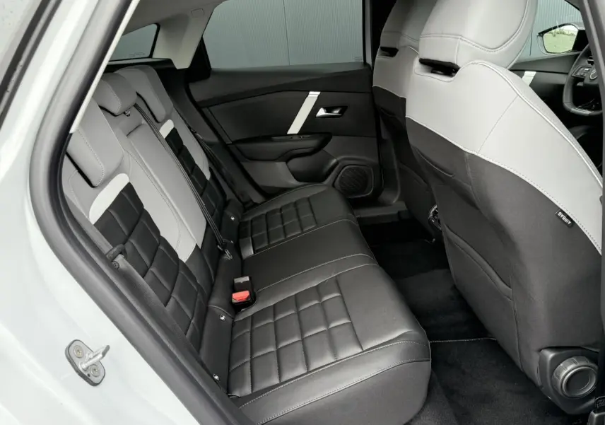 Vue intérieure arrière côté gauche des sièges bicolores noir et gris du Citroën C4 NV Hybrid 2025 avec appuie-têtes intégrés.