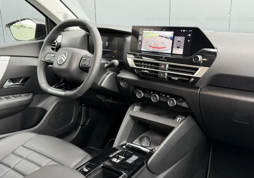Intérieur avant droit du Citroën C4 hybride 2025 avec tableau de bord noir, écran tactile et volant cuir.