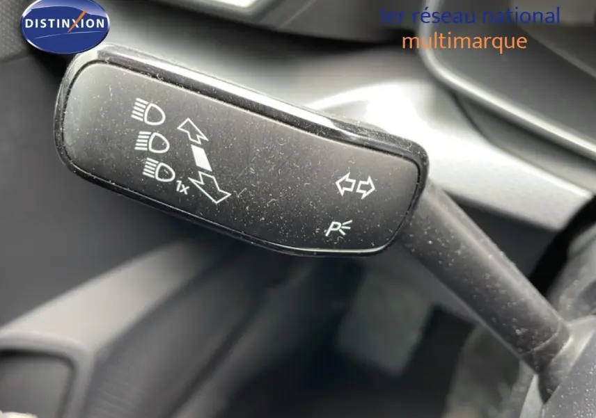 Gros plan sur la manette de clignotant et feux d’un SEAT LEON ST gris métallique, intérieur noir visible en arrière-plan.