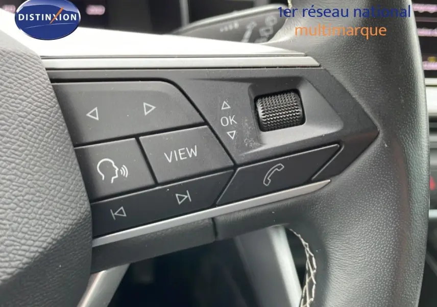 Gros plan sur les commandes au volant cuir noir de la SEAT LEON ST 2025, boutons multifonctions et molette tactile.