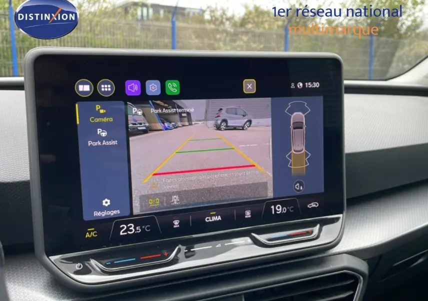 Vue rapprochée de l’écran tactile intérieur du SEAT LEON ST gris magnétique, affichant la caméra de recul et l’aide au stationnement.