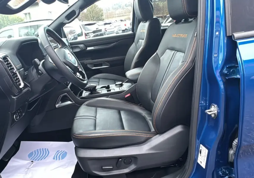 Vue intérieure côté conducteur du Ford Ranger 2025 bleu lightning, sièges cuir noirs avec surpiqûres orange Wildtrak.