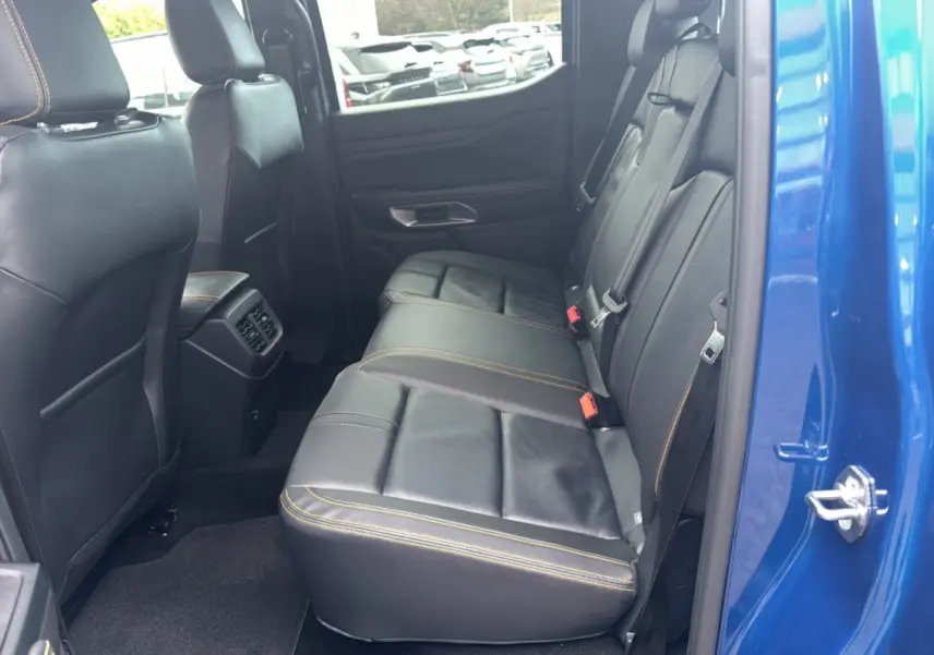Vue côté droit de l'intérieur arrière du Ford Ranger 2025 bleu lightning avec sièges en cuir noir et surpiqûres orange.