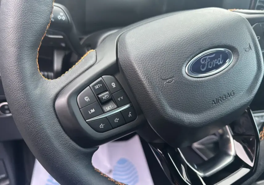 Gros plan sur le volant cuir noir avec commandes multifonctions du Ford Ranger 2025, version Wildtrak Plus.