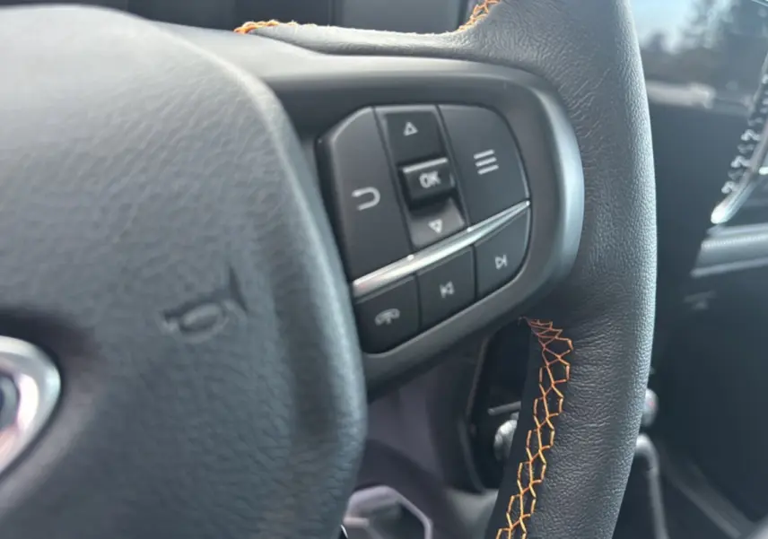Gros plan sur le volant cuir noir avec surpiqûres orange et commandes multifonctions du Ford Ranger 2025.