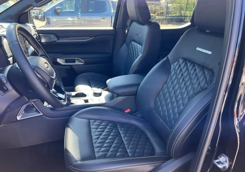 Vue intérieure côté gauche du Ford Ranger 3.0 V6 Platinum avec sièges cuir noirs matelassés et logo Platinum.