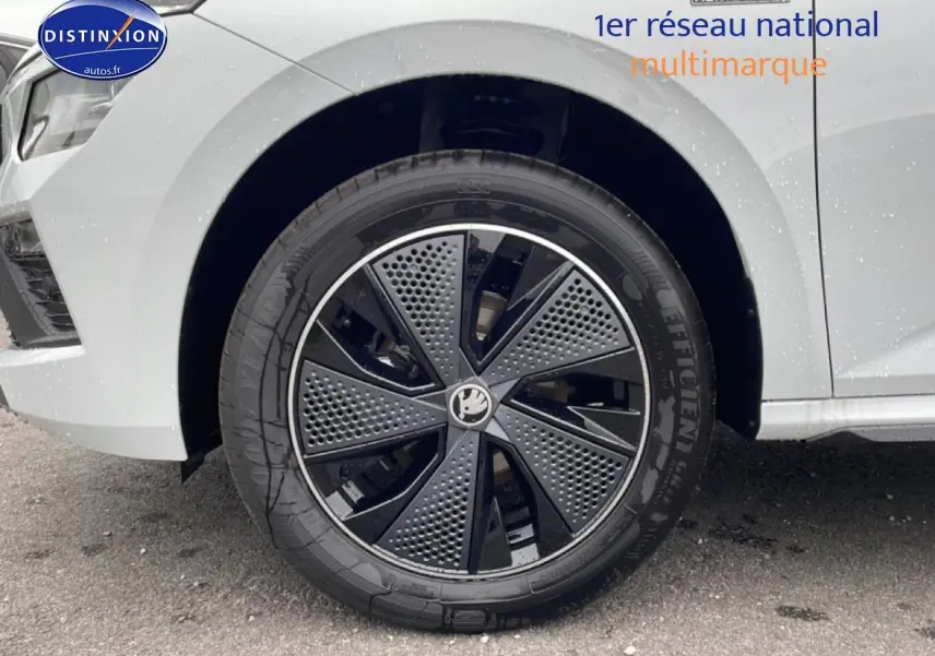 Gros plan sur la roue avant droite du Skoda Kamiq blanc nacré avec jante alu noire et grise au design moderne.