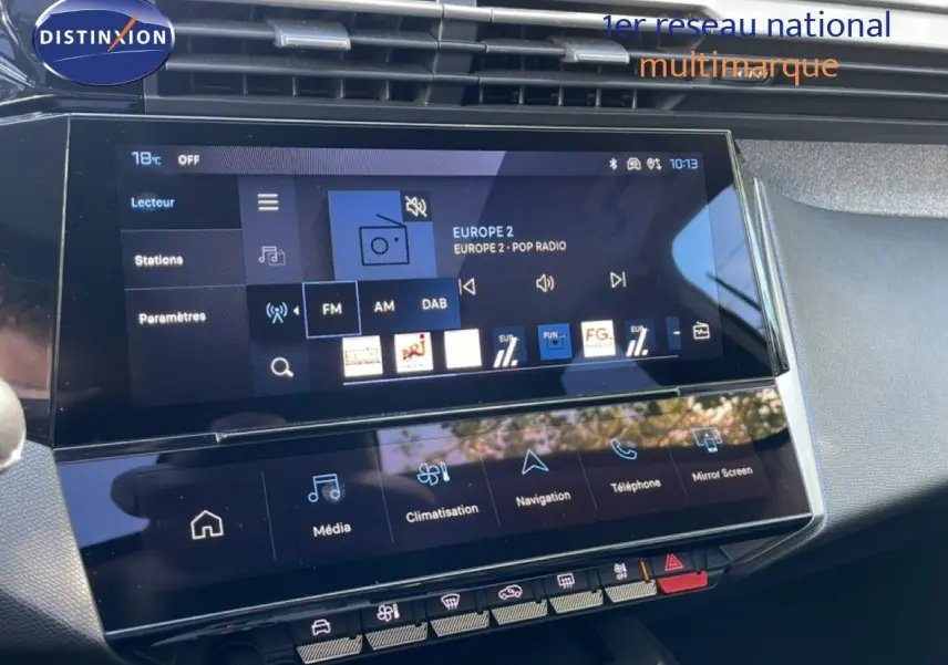 Vue rapprochée de l'écran tactile central et de la console de la Peugeot 308 SW Hybrid gris Artense, affichant les options multimédia et climatisation.